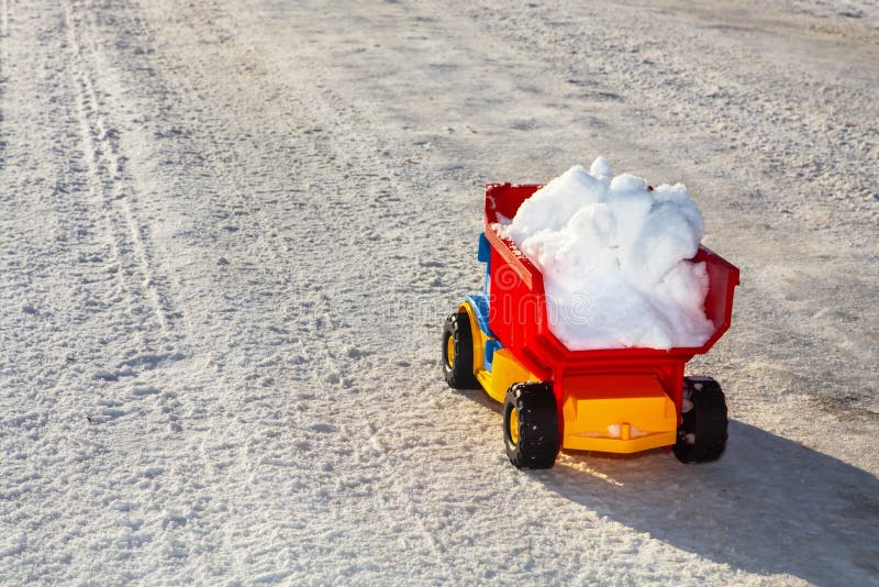 Toy truck removes snow on the road in winter. Toy truck removes snow on the road in winter