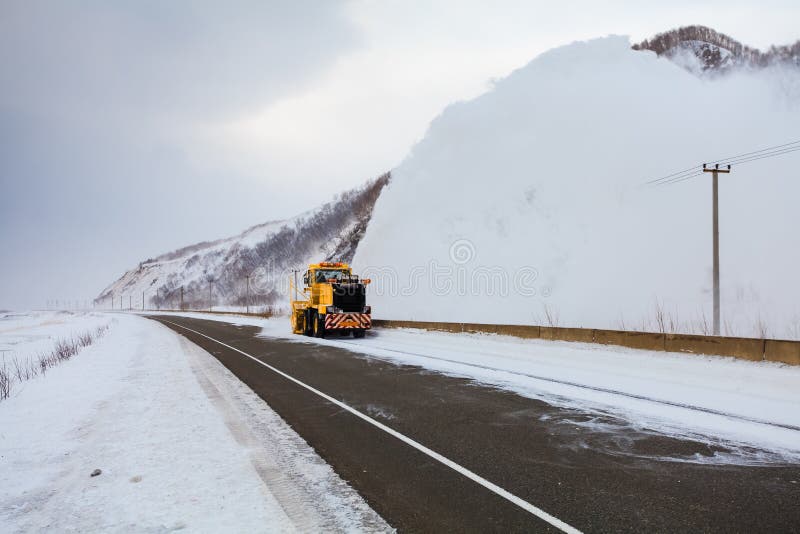 Il camion di rimozione di neve del camion dello spazzaneve sta rimuovendo la neve dalla strada principale immagine stock libera da diritti Il camion di rimozione di neve del camion dello spazzaneve sta rimuovendo la neve dalla strada principale immagine stock libera da diritti