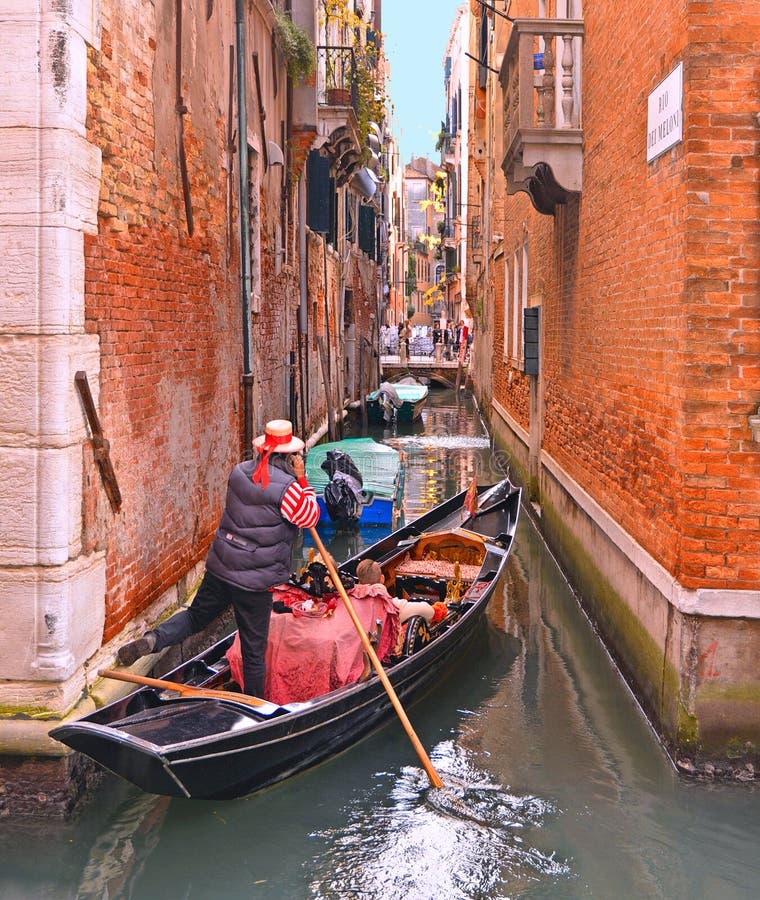 Il canale dell'acqua di Venezia, uomo dell'Italia con la gondola sta remando sui turisti di trasporto di un canale stretto intorn fotografia stock libera da diritti Il canale dell'acqua di Venezia, uomo dell'Italia con la gondola sta remando sui turisti di trasporto di un canale stretto intorn fotografia stock libera da diritti