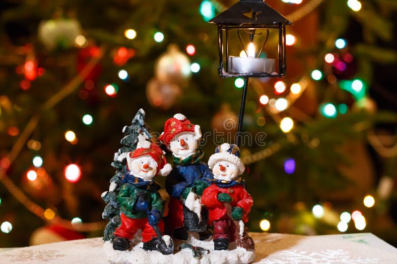 Il candeliere allegro dei pupazzi di neve con la candela bruciante davanti all'albero di Natale si accende fotografia stock Il candeliere allegro dei pupazzi di neve con la candela bruciante davanti all'albero di Natale si accende fotografia stock