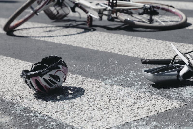 Il casco e le automobili rotte si rispecchiano accanto alla bicicletta rotta sul passaggio pedonale