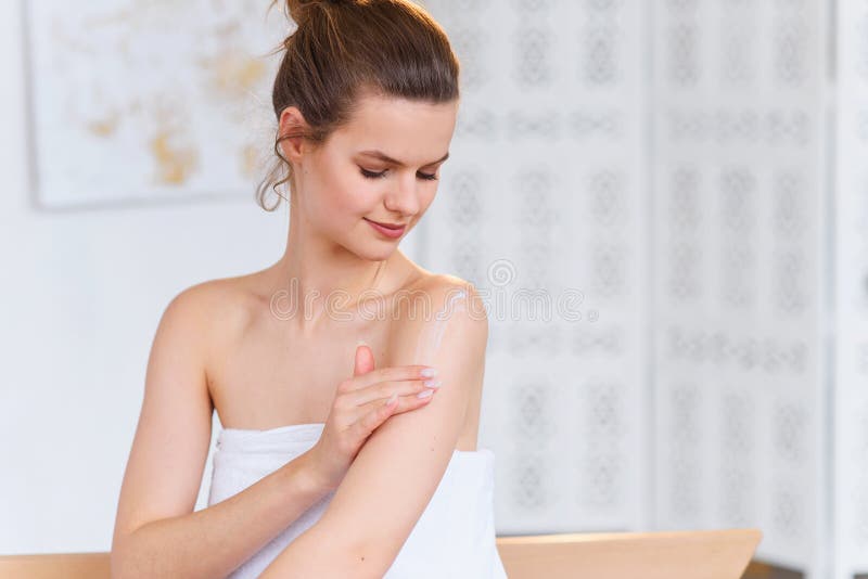 Il caucasianwoman sveglio applica la crema naturale dell'idratante su pelle liscia delicata dopo sui precedenti bianchi del salon fotografia stock Il caucasianwoman sveglio applica la crema naturale dell'idratante su pelle liscia delicata dopo sui precedenti bianchi del salon fotografia stock