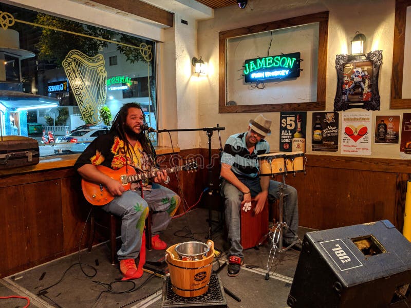 Waikiki - March 2, 2017: Guitarist Reggae Musician Keith Batlin sings and plays with drummer as he jams at the Kelley O& x27;Neil& x27;s in Waikiki, Hawaii oneils duet celebration club concert crowd disco entertainment event hair hand instrument light live night irish people perform performance person player hat chair rhythm rock roll show silhouette singer smoke song sound stage star vocal young guidance honolulu bar lewers dreadlocks motion drums. Waikiki - March 2, 2017: Guitarist Reggae Musician Keith Batlin sings and plays with drummer as he jams at the Kelley O& x27;Neil& x27;s in Waikiki, Hawaii oneils duet celebration club concert crowd disco entertainment event hair hand instrument light live night irish people perform performance person player hat chair rhythm rock roll show silhouette singer smoke song sound stage star vocal young guidance honolulu bar lewers dreadlocks motion drums