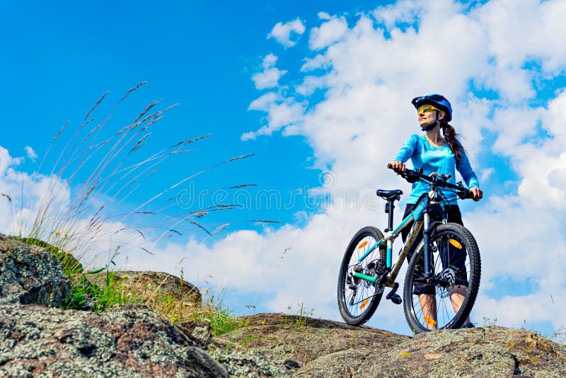 Il ciclista della donna sta sulla sommità con il suo mountain bike immagini stock Il ciclista della donna sta sulla sommità con il suo mountain bike immagini stock