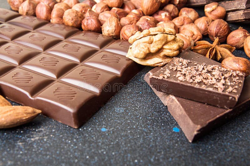 Il cioccolato collega, nocciola, trucioli del cioccolato, noce sulle sedere scure fotografie stock Il cioccolato collega, nocciola, trucioli del cioccolato, noce sulle sedere scure fotografie stock