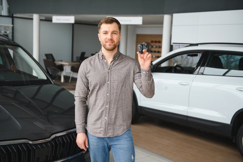 Il cliente mostra la nuova chiave dell'auto nello showroom di DealerNet immagine stock