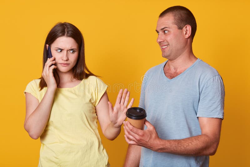 Il colpo dell'interno degli sguardi tristi della donna con l'espressione turbata al tipo offre il suo coffe asportabile, ha espre fotografia stock libera da diritti Il colpo dell'interno degli sguardi tristi della donna con l'espressione turbata al tipo offre il suo coffe asportabile, ha espre fotografia stock libera da diritti