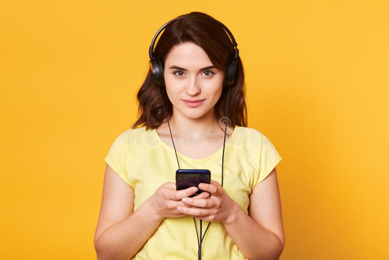 Il colpo di giovane ragazza mora con le cuffie, pronto ad ascoltare musica, esamina derictly la macchina fotografica con espressi immagini stock Il colpo di giovane ragazza mora con le cuffie, pronto ad ascoltare musica, esamina derictly la macchina fotografica con espressi immagini stock