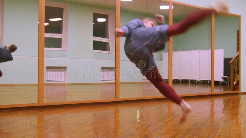 Il combattente maschio biondo esegue i trucchi marziali con gli elementi di ballo nella palestra di sport