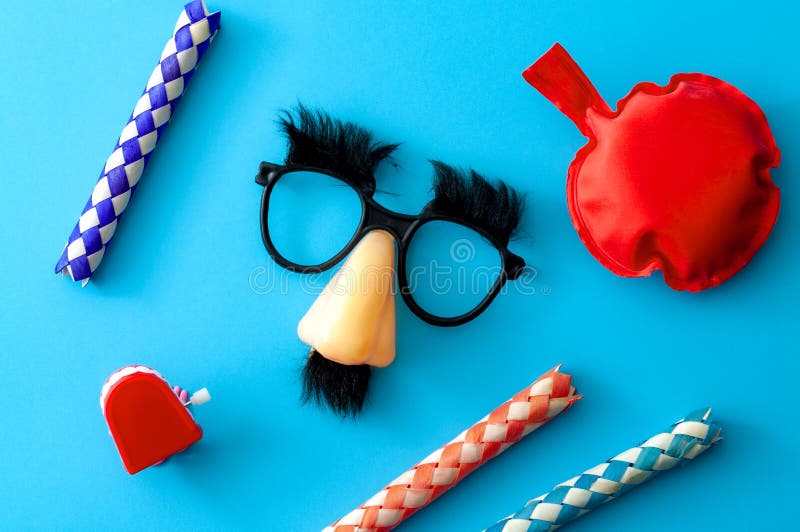 Comical prank, April fools practical joke and goofy disguise concept farting bag, chattering teeth, chinese finger trap and novelty glasses with fake nose and eyebrows isolated on blue background. Comical prank, April fools practical joke and goofy disguise concept farting bag, chattering teeth, chinese finger trap and novelty glasses with fake nose and eyebrows isolated on blue background