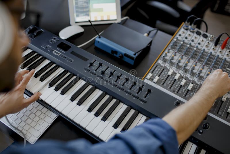 Il compositore usa i tasti del pianoforte nello studio di registrazione. l'uomo della tecnologia di produzione musicale sta lavora