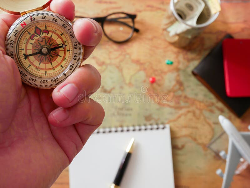 Il concetto di progettazione di viaggio, bugie della bussola della tenuta della mano viaggia e costumi degli accessori Passaporti fotografia stock libera da diritti Il concetto di progettazione di viaggio, bugie della bussola della tenuta della mano viaggia e costumi degli accessori Passaporti fotografia stock libera da diritti