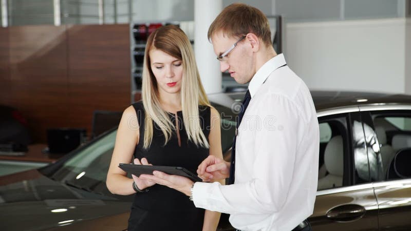 Il consulente in materia femminile del negozio del cliente dice circa l'automobile nel centro dell'automobile