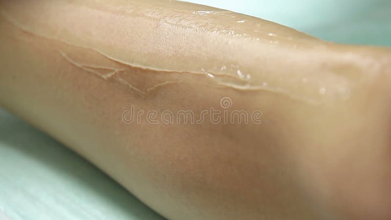 Il cosmetologo applica il gel ai piedi pazienti del ` s prima della procedura di epilation