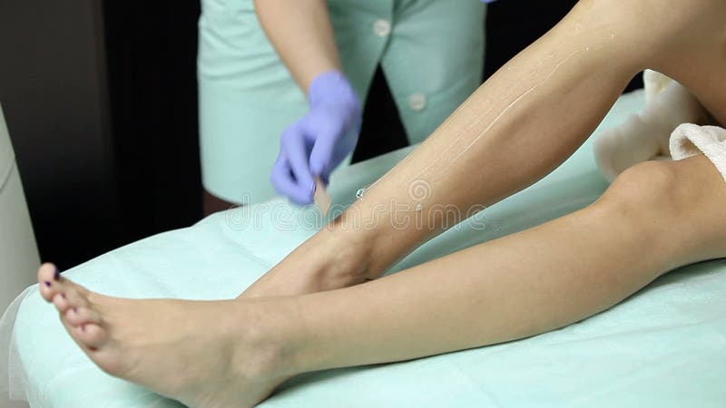 Il cosmetologo applica il gel ai piedi pazienti del ` s prima della procedura di epilation