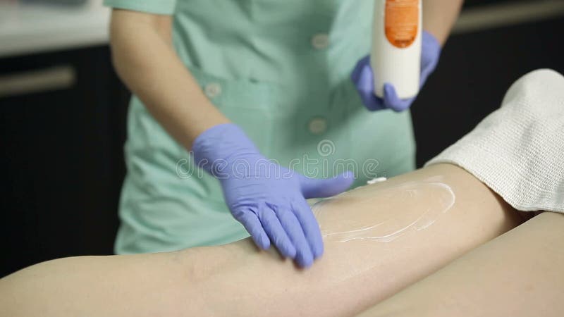 Il cosmetologo applica la crema ai piedi pazienti del ` s dopo la procedura di epilation