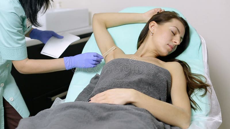 Il cosmetologo si applica il gel alle ascelle del paziente prima della procedura di epilation