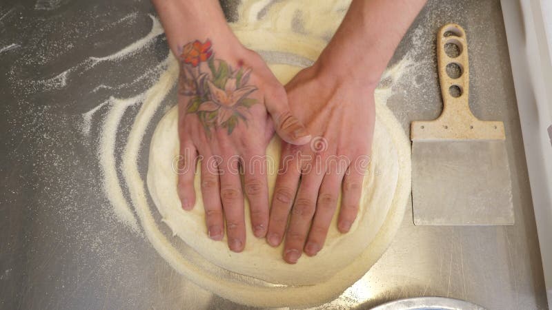 Il cuoco ruota l'impasto in cerchio con le mani e forma una pizza.