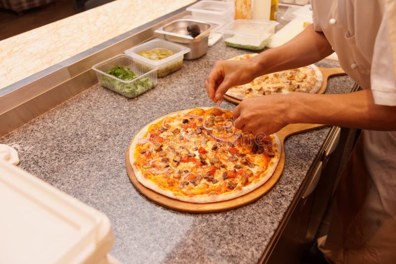 Il cuoco unico sta servendo la pizza immagine stock libera da diritti Il cuoco unico sta servendo la pizza immagine stock libera da diritti