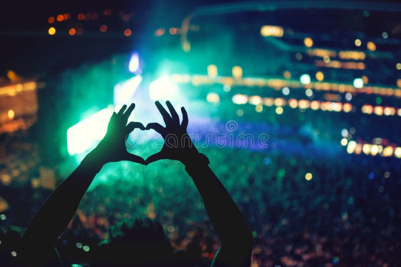 Il cuore ha modellato le mani al concerto, amando l'artista ed il festival Concerto di musica con le luci e la siluetta di un god Il cuore ha modellato le mani al concerto, amando l'artista ed il festival Concerto di musica con le luci e la siluetta di un god