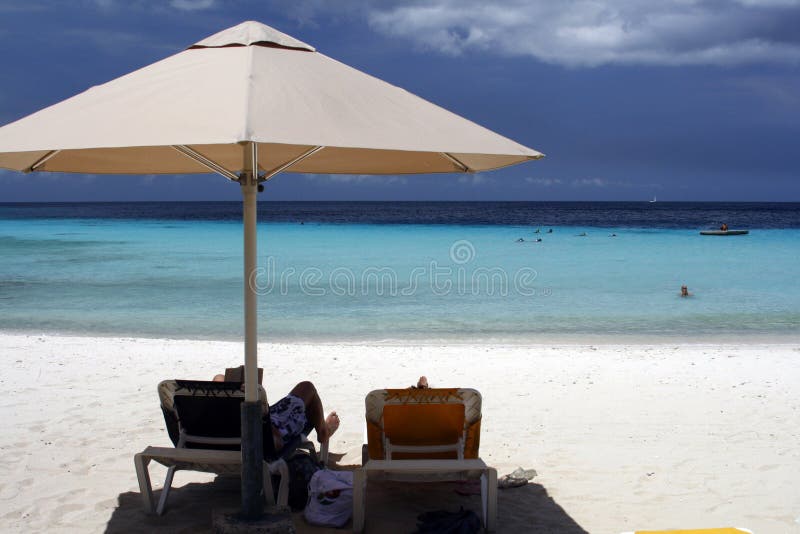 Il Curacao - distendendosi sotto un ombrello di spiaggia fotografia stock libera da diritti