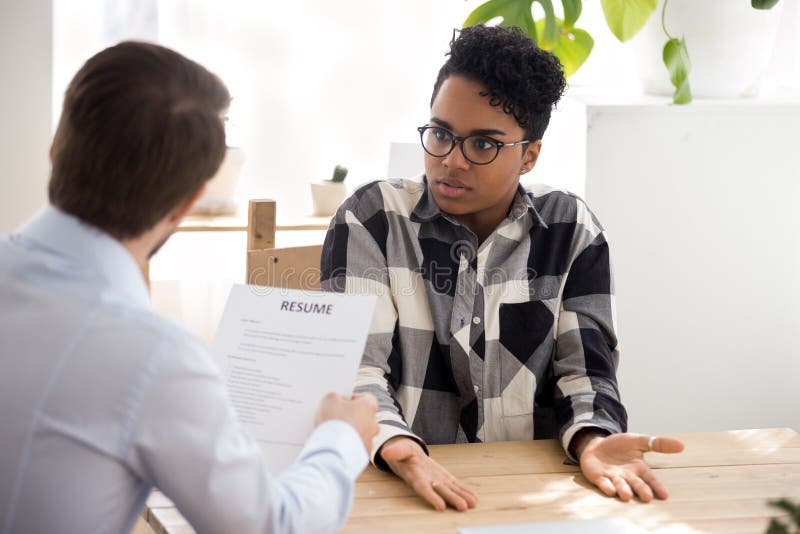 Il datore di lavoro maschio e la candidata nera hanno malinteso a fotografia stock Il datore di lavoro maschio e la candidata nera hanno malinteso a fotografia stock