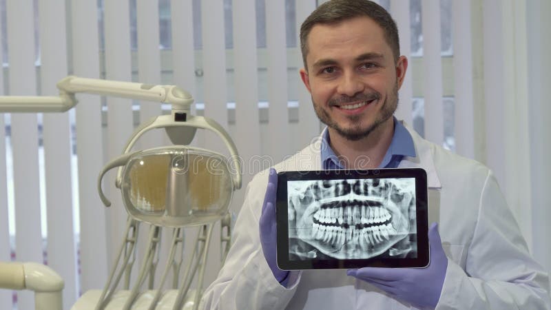 Il dentista dimostra i raggi x dei denti umani sulla sua compressa immagini stock libere da diritti Il dentista dimostra i raggi x dei denti umani sulla sua compressa immagini stock libere da diritti