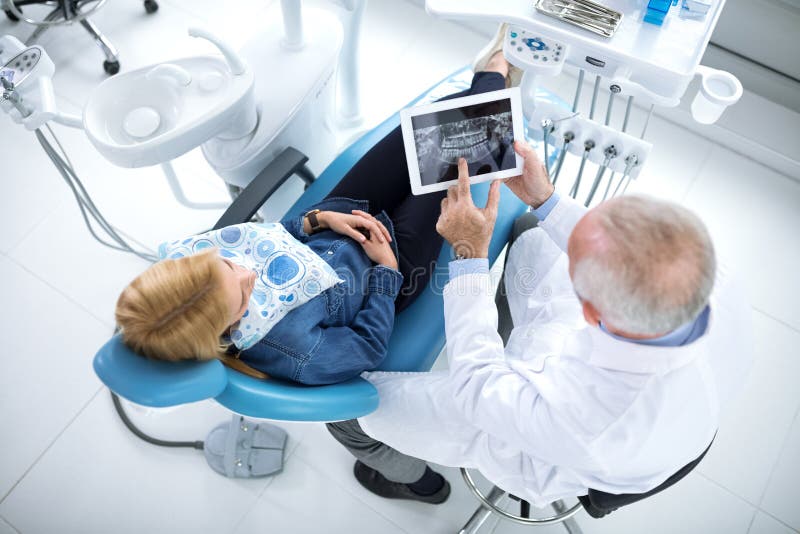 Il dentista mostra il paziente di cui i denti devono essere riparati fotografie stock libere da diritti Il dentista mostra il paziente di cui i denti devono essere riparati fotografie stock libere da diritti