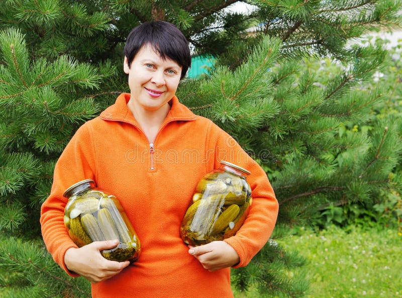 il Donna-giardiniere tiene due vasi con il cetriolo immagini stock il Donna-giardiniere tiene due vasi con il cetriolo immagini stock