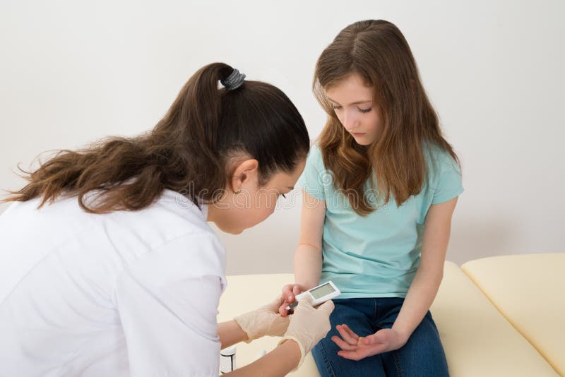 Il dottore Measuring Blood Sugar Level Of Girl fotografia stock libera da diritti Il dottore Measuring Blood Sugar Level Of Girl fotografia stock libera da diritti