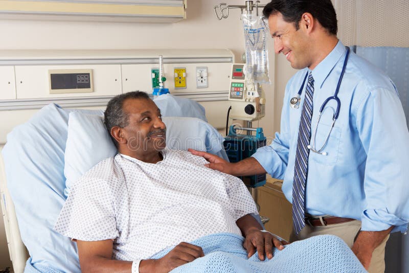 Male Doctor Visiting Senior Male Patient On Ward Smiling. Male Doctor Visiting Senior Male Patient On Ward Smiling