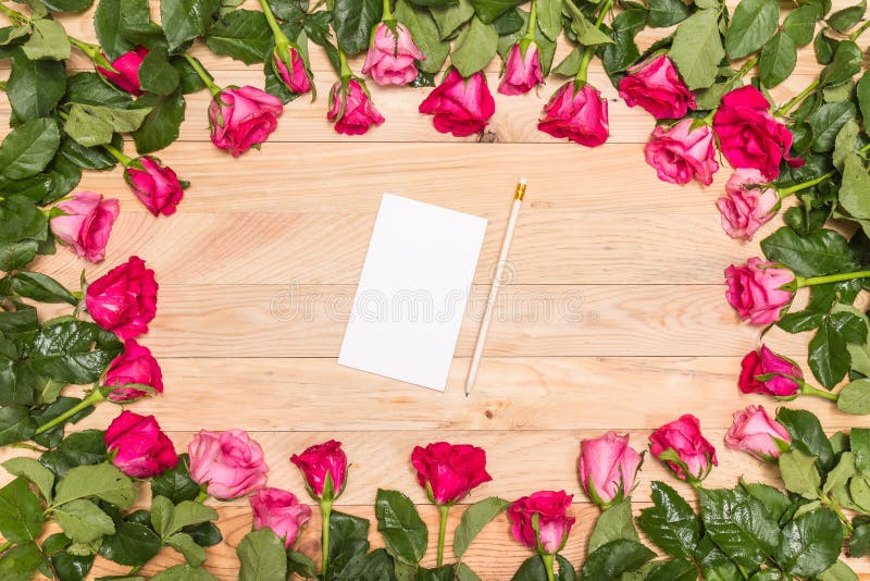 Top view fresh pink rose flower and empty white note book on wooden deck. For love or valentine day concept. Top view fresh pink rose flower and empty white note book on wooden deck. For love or valentine day concept