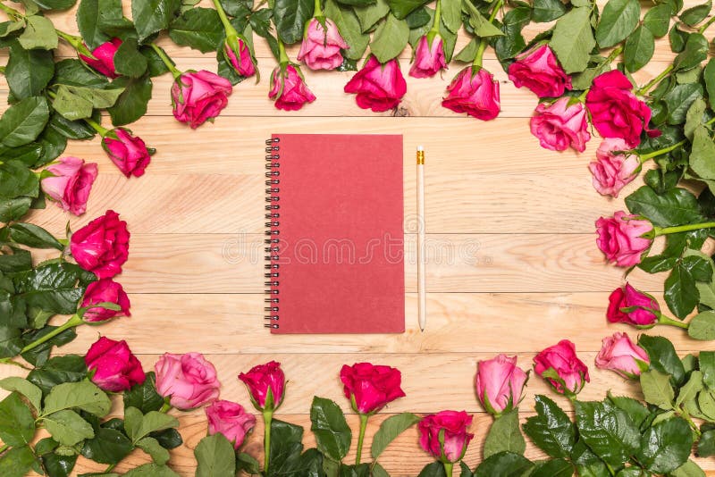 Top view fresh pink rose flower and empty white note book on wooden deck. For love or valentine day concept. Top view fresh pink rose flower and empty white note book on wooden deck. For love or valentine day concept