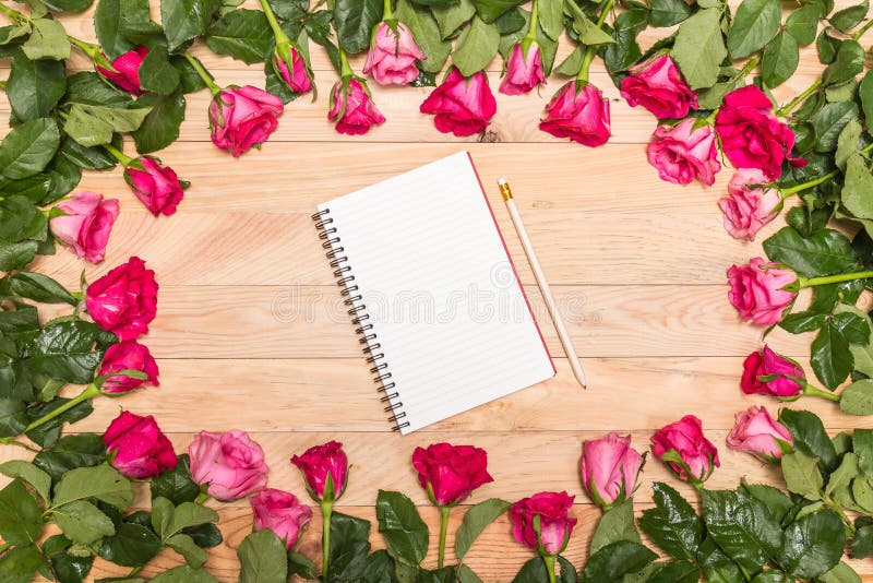 Top view fresh pink rose flower and empty white note book on wooden deck. For love or valentine day concept. Top view fresh pink rose flower and empty white note book on wooden deck. For love or valentine day concept