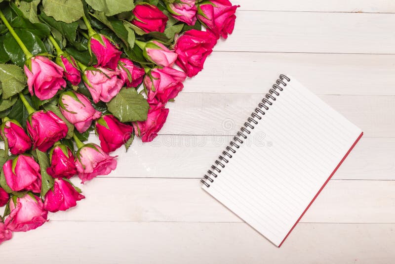 Top view fresh pink rose flower and empty white note book on wooden deck. For love or valentine day concept. Top view fresh pink rose flower and empty white note book on wooden deck. For love or valentine day concept