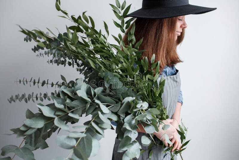 Il fiorista fa un mazzo Processo di lavoro donna che tiene un mazzo dell'eucalyptus in mani immagini stock libere da diritti Il fiorista fa un mazzo Processo di lavoro donna che tiene un mazzo dell'eucalyptus in mani immagini stock libere da diritti