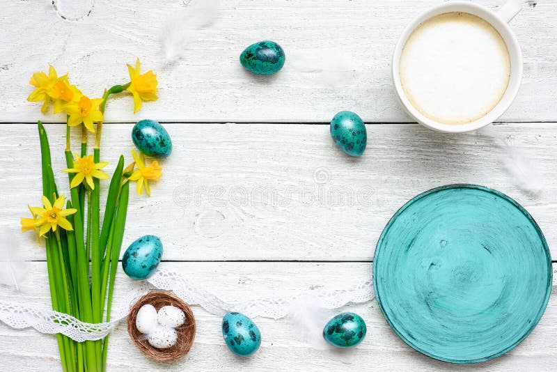 Il fondo di Pasqua con le uova di Pasqua, i fiori della molla, tazza di cappuccino ed e svuota il piatto blu fotografie stock libere da diritti Il fondo di Pasqua con le uova di Pasqua, i fiori della molla, tazza di cappuccino ed e svuota il piatto blu fotografie stock libere da diritti