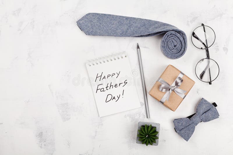 Happy Fathers Day background with notebook, gift, glasses, necktie and bowtie on white table top view in flat lay style. Happy Fathers Day background with notebook, gift, glasses, necktie and bowtie on white table top view in flat lay style