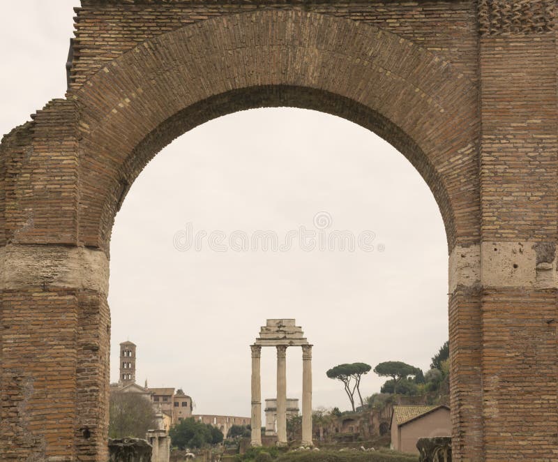 Il Forum romano rovina la vista attraverso l'arco di Roma Edifici antichi italiani e marchi di fabbrica fotografia stock libera da diritti Il Forum romano rovina la vista attraverso l'arco di Roma Edifici antichi italiani e marchi di fabbrica fotografia stock libera da diritti