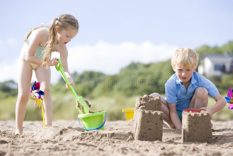 Il fratello e la sorella alla spiaggia che fa la sabbia fortifica