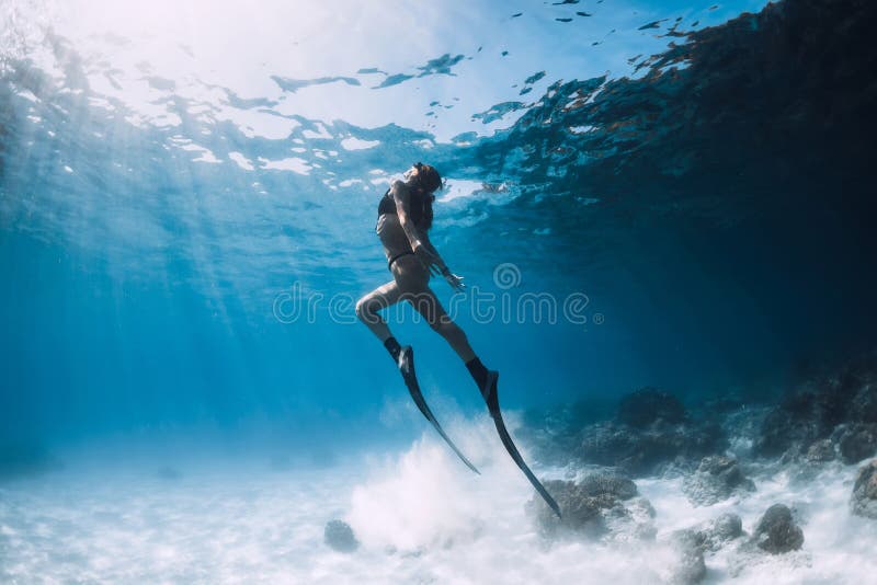 Il freediver della donna scivola sopra il mare sabbioso con le alette fotografia stock libera da diritti Il freediver della donna scivola sopra il mare sabbioso con le alette fotografia stock libera da diritti