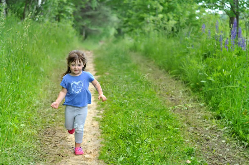 Il funzionamento della bambina nella foresta di fioritura soleggiata scherza il gioco all'aperto Divertimento di estate per la fa immagine stock libera da diritti Il funzionamento della bambina nella foresta di fioritura soleggiata scherza il gioco all'aperto Divertimento di estate per la fa immagine stock libera da diritti