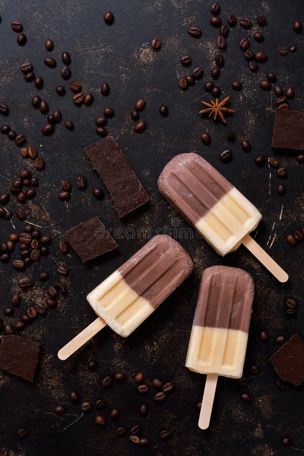 Il gelato del caffè su un bastone, fette del cioccolato, ha sparso i chicchi di caffè, fondo di marrone scuro Vista superiore, sp fotografia stock libera da diritti Il gelato del caffè su un bastone, fette del cioccolato, ha sparso i chicchi di caffè, fondo di marrone scuro Vista superiore, sp fotografia stock libera da diritti