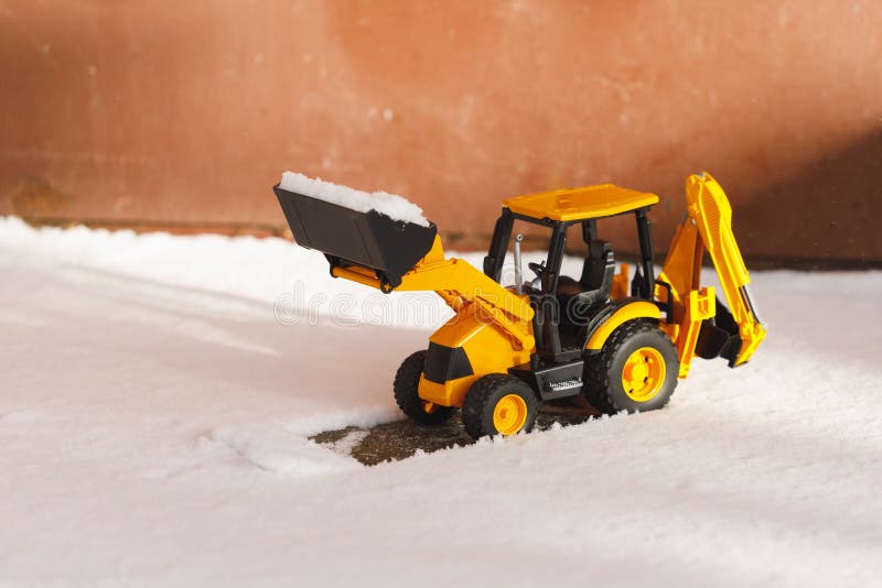 Tractor toy removes snow out of the way, close-up view. Tractor toy removes snow out of the way, close-up view