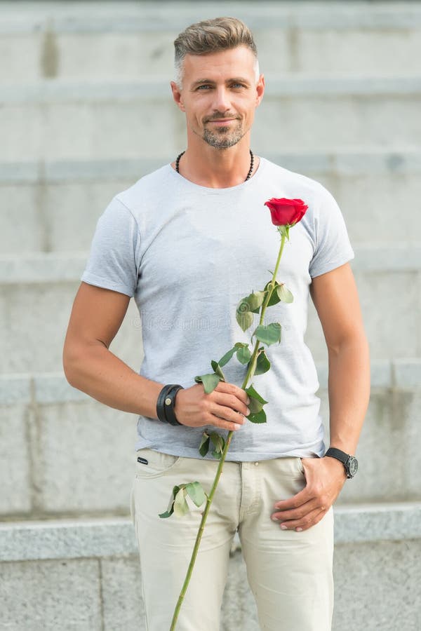 Il giorno delle donne felici a tutte le donne adorabili Uomo barbuto che tiene il fiore del giorno delle donne in primavera Uomo fotografia stock Il giorno delle donne felici a tutte le donne adorabili Uomo barbuto che tiene il fiore del giorno delle donne in primavera Uomo fotografia stock