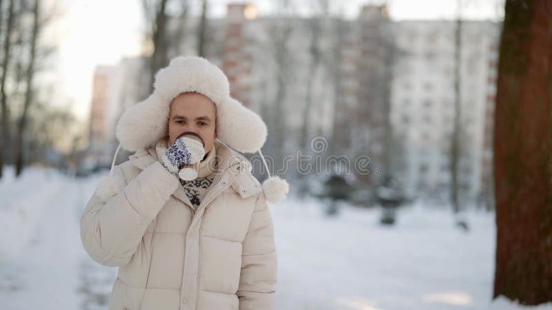 Il giovane cammina in città d'inverno bevendo tè caldo o caffè da tazza di carta stock footage