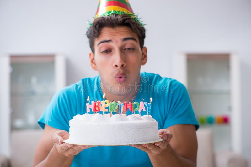 Il giovane che celebra compleanno da solo a casa fotografia stock Il giovane che celebra compleanno da solo a casa fotografia stock