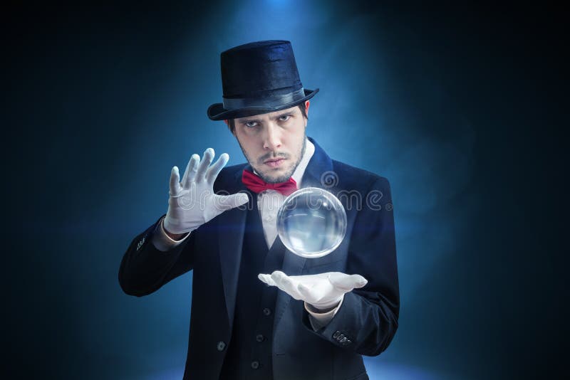 Il giovane illusionista, mago o indovino sta predicendo il futuro con la sfera di cristallo fotografia stock libera da diritti