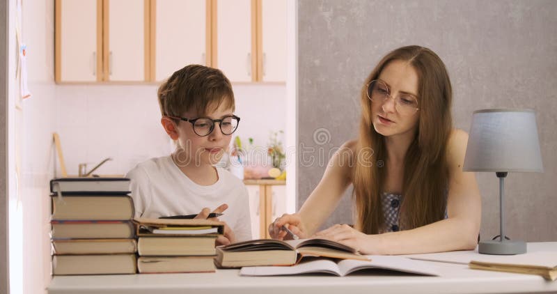 Il giovane insegnante studia con uno studente. madre e figlio fanno i compiti. tutor spiega l'argomento a figlio.