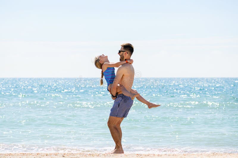 Il giovane padre gioca con la figlia sulla spiaggia di mare fotografie stock
